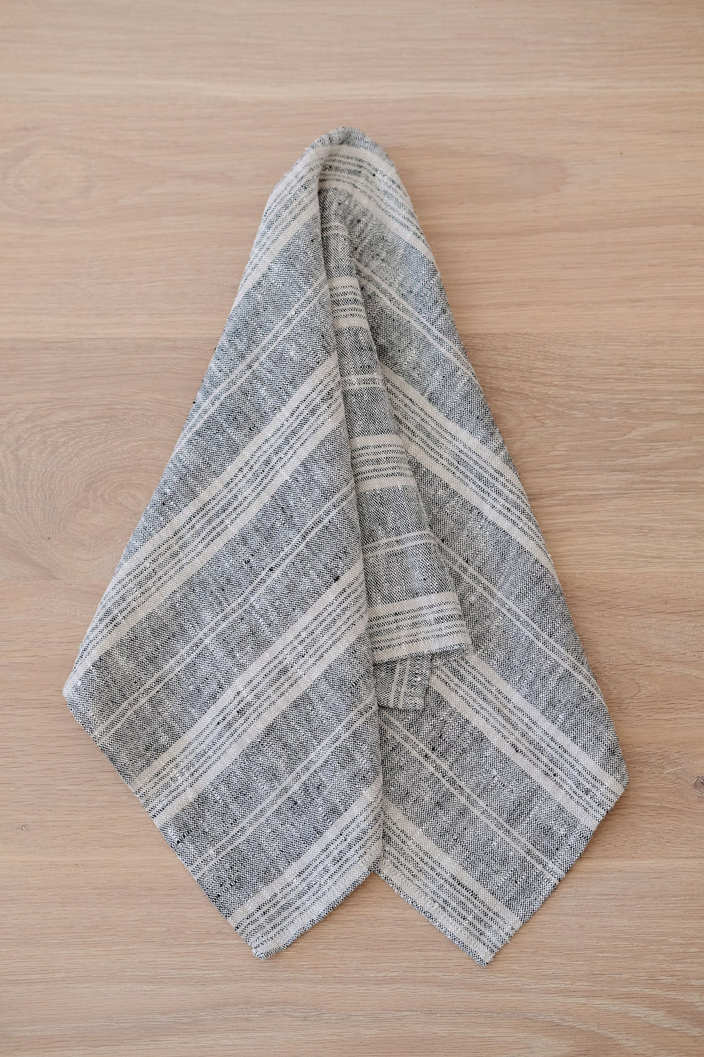 Blue and grey striped linen hand towel hanging on wooden surface