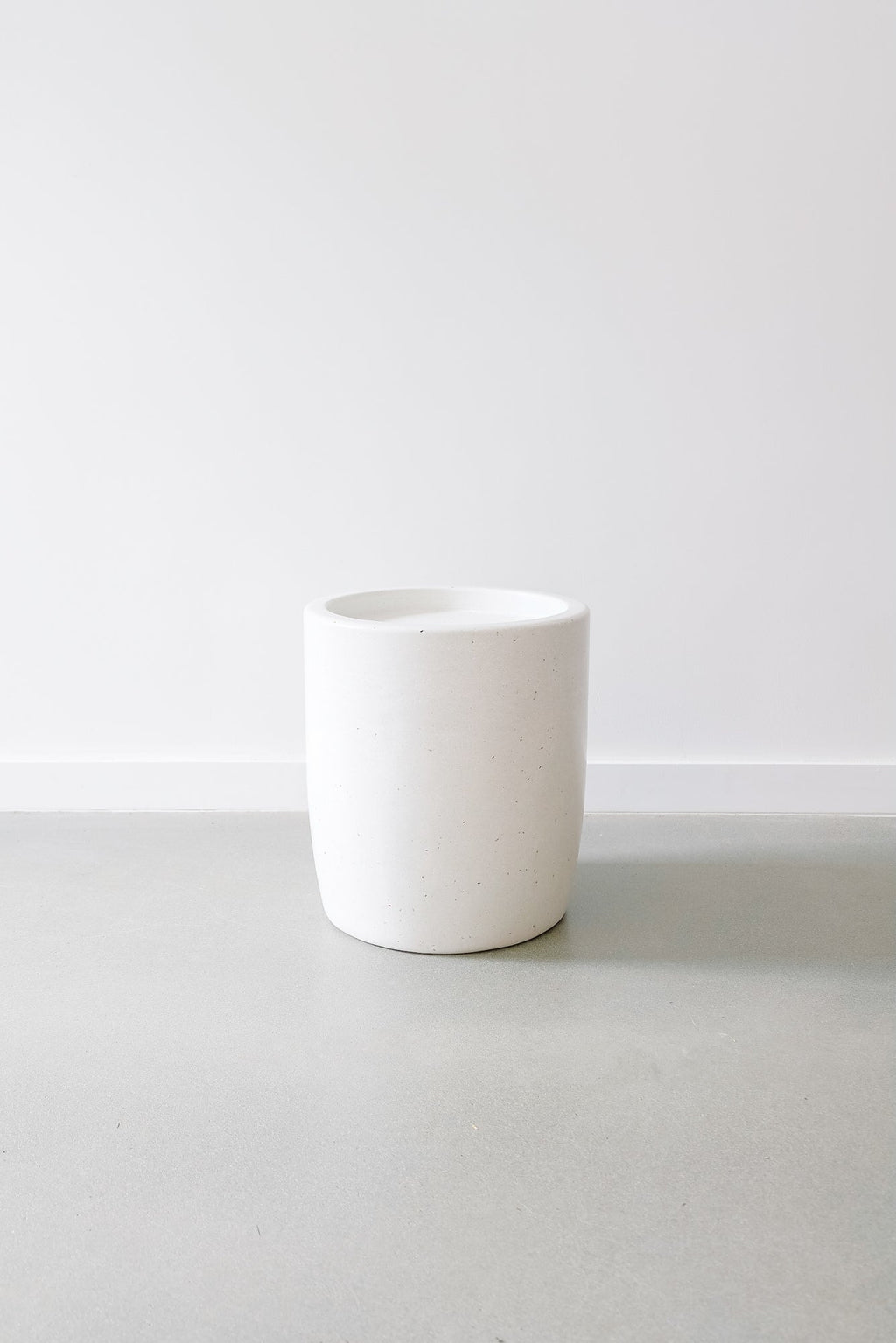 Minimalist white Abalone Terrazzo Side Table with smooth cylindrical design on gray floor