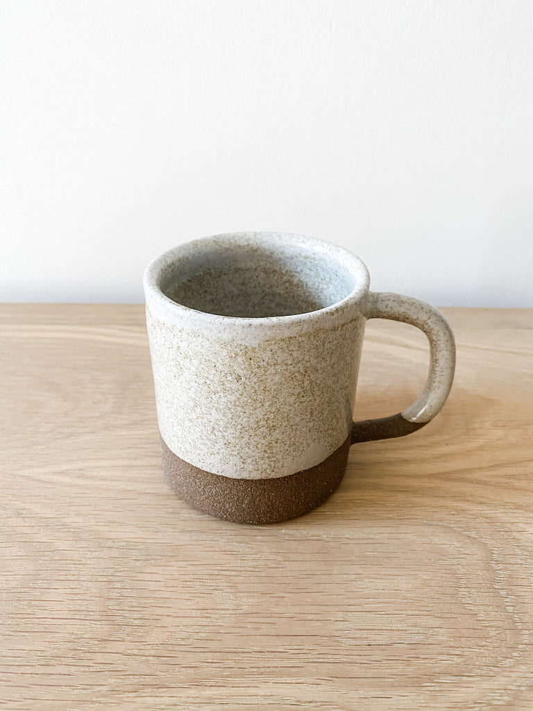 Front slightly angled view of Uzumati Ceramic Snow Creek Mug on white oak against a white wall - Saffron and Poe