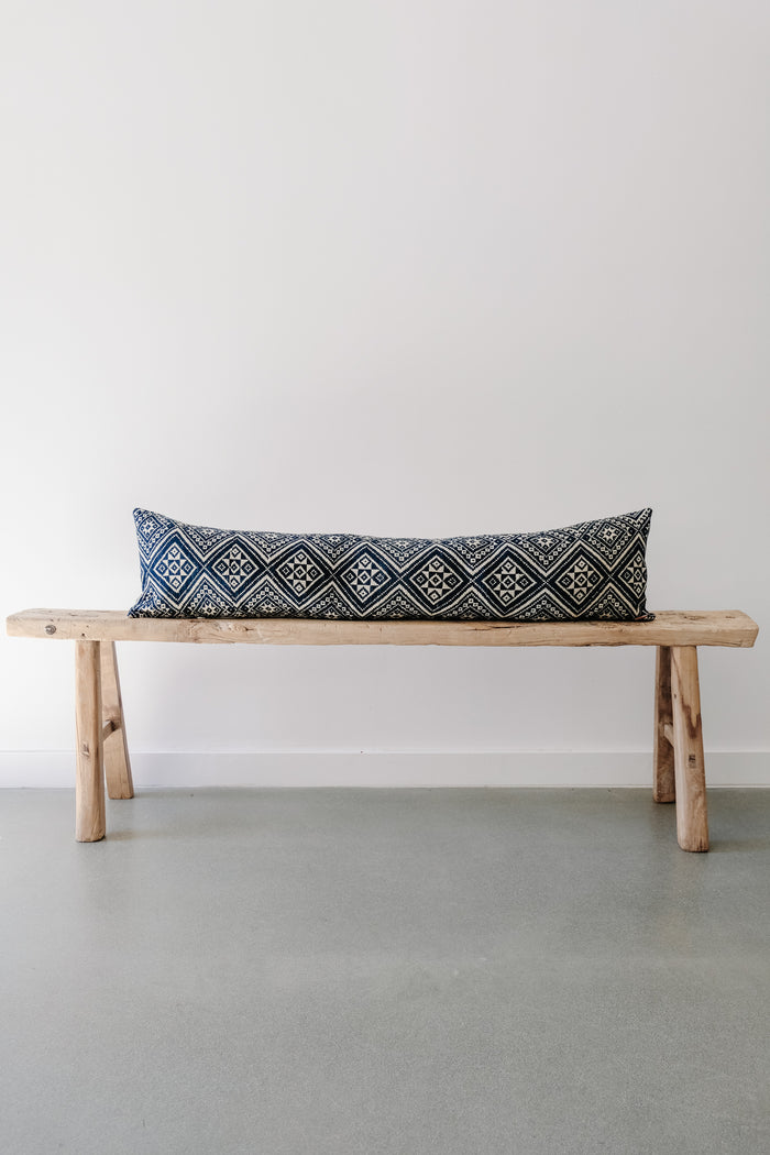 Front view of Antique Miao Lumbar Pillow on an Extra Long Antique Chinese Bench against a white wall. - Saffron and Poe