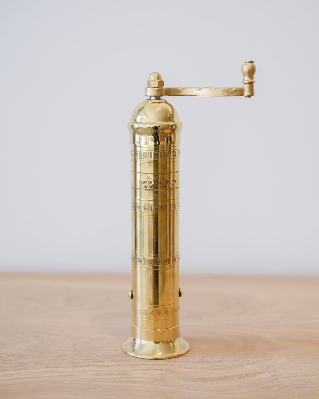 9" Atlas Brass Pepper Grinder standing on wooden surface with adjustable grinding handle