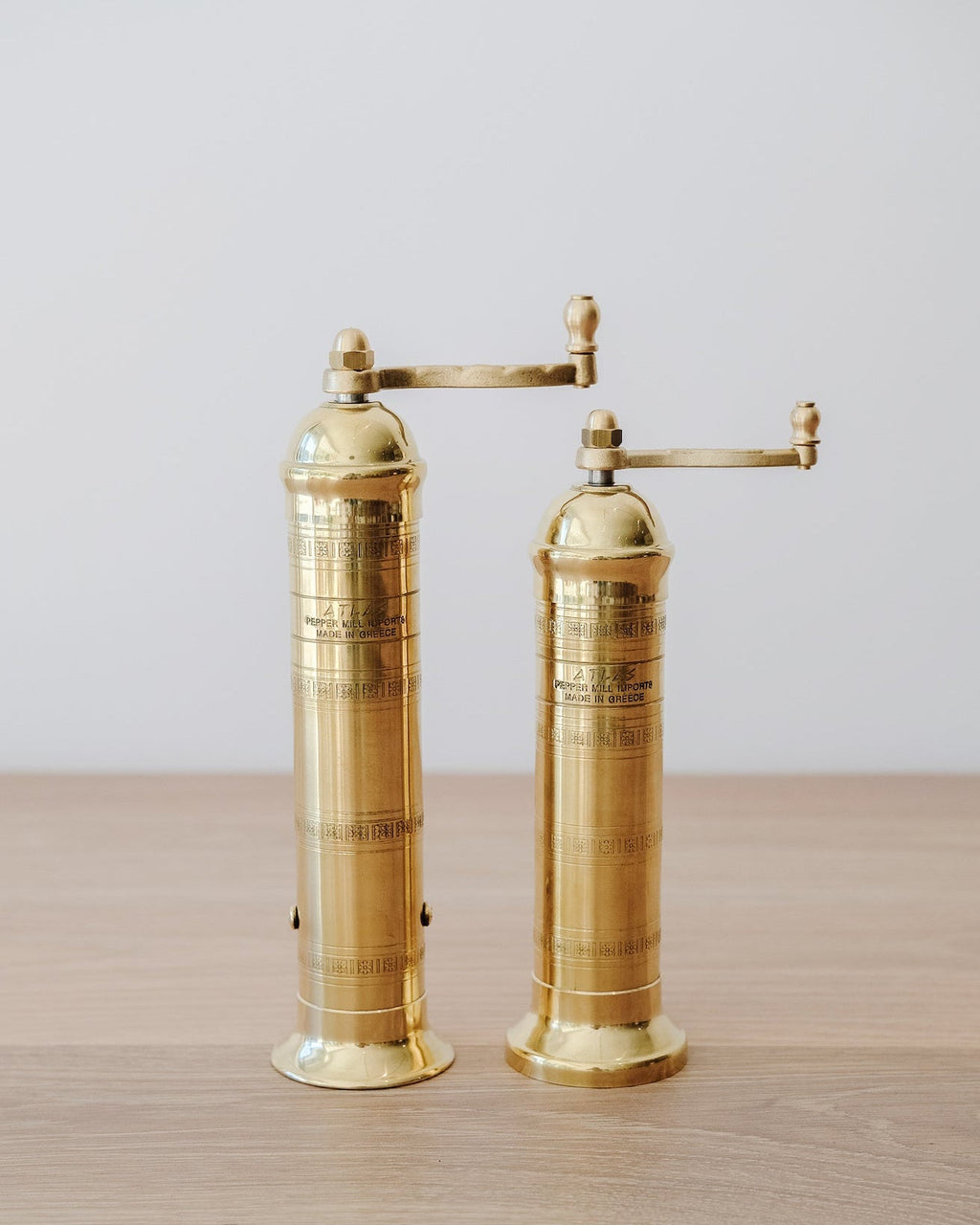 9" Atlas Brass Pepper Grinder standing on wooden surface with adjustable grinding handle