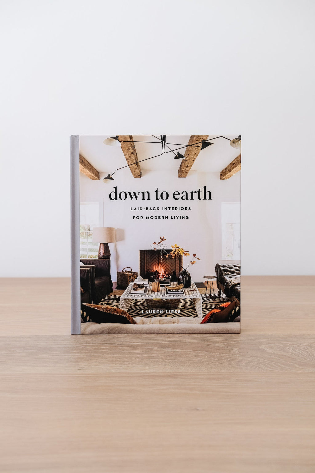 Down to Earth book cover featuring cozy, nature-inspired interior design with exposed wooden beams and a fireplace