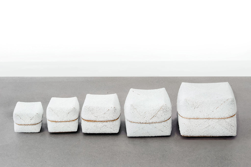 Set of five hand-beaded Bali baskets in solid white arranged in a row on a gray surface