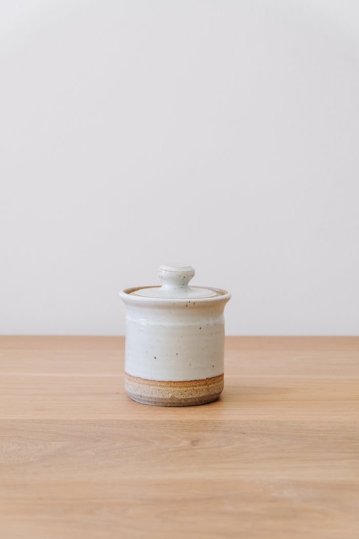 Front view of Hand Thrown Ceramic Sugar Jar on an oak table against a white wall. - Saffron and Poe