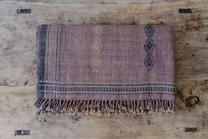 Front view of Handwoven Bhujodi Blanket Single Panel - Rust on an Antique Chinese Coffee Table. - Saffron and Poe