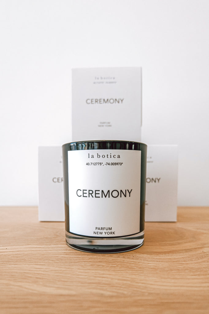 One La Botica Ceremony Candle in front of three stacked Ceremony Candles against a white background on an oak wood surface - Saffron and Poe