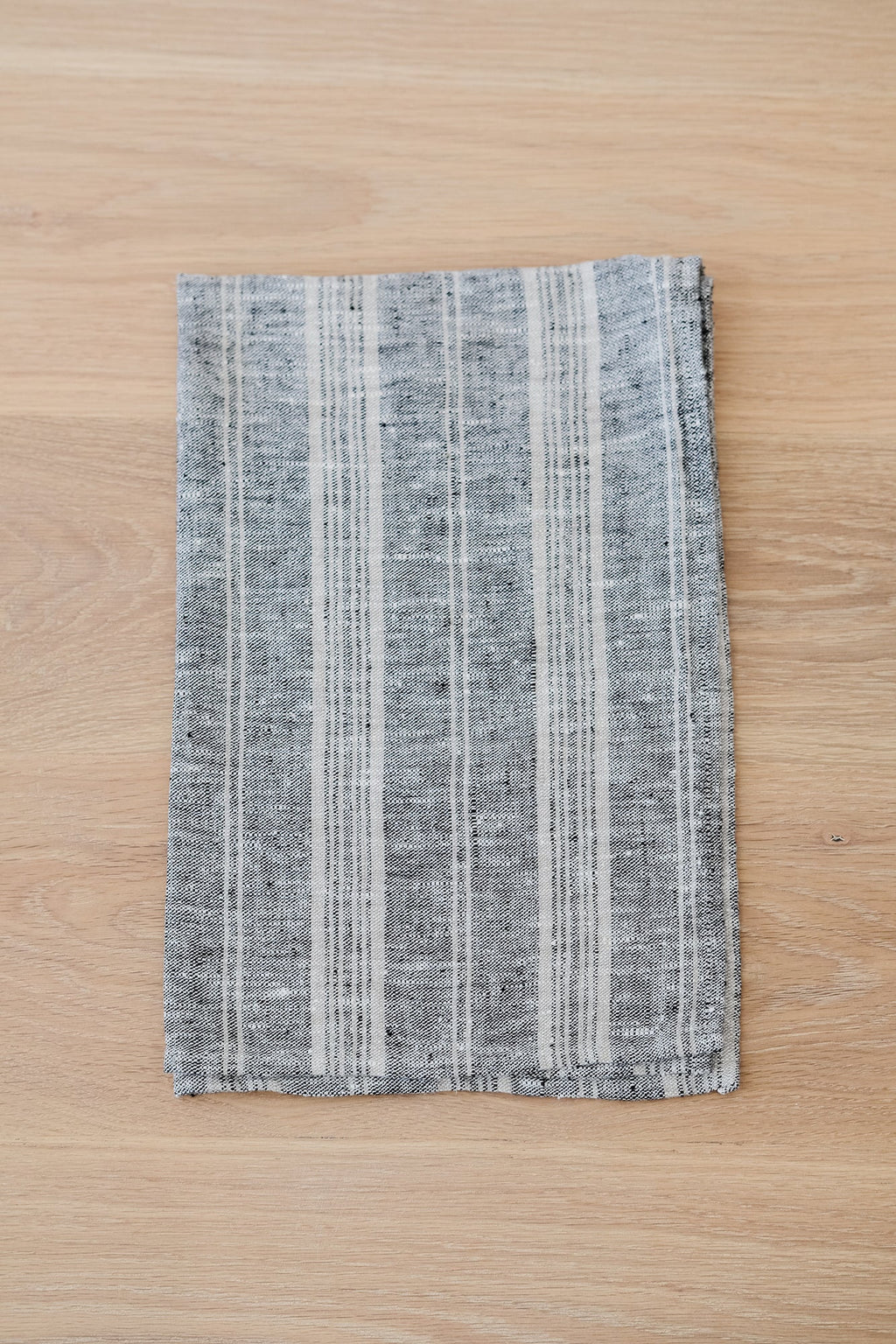Blue and grey striped linen hand towel on wooden surface