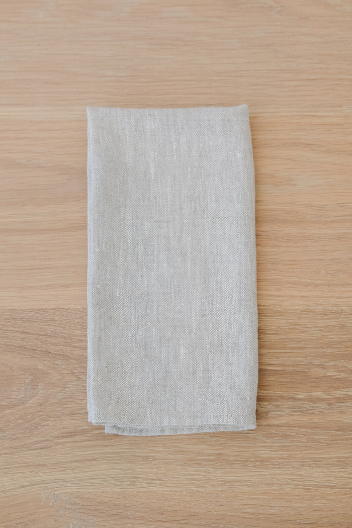 Front Natural Linen Napkin on a White Oak Dining Table. - Saffron and Poe