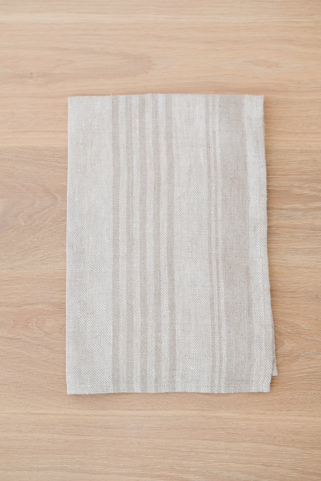 Natural stripe linen hand towel in earth tones on wooden surface