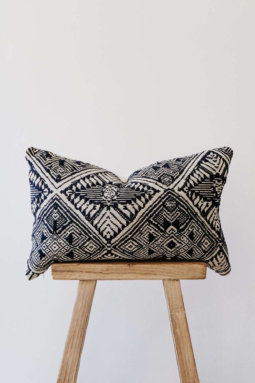 Antique Miao Lumbar Pillow with traditional black and white woven geometric patterns on wooden stool
