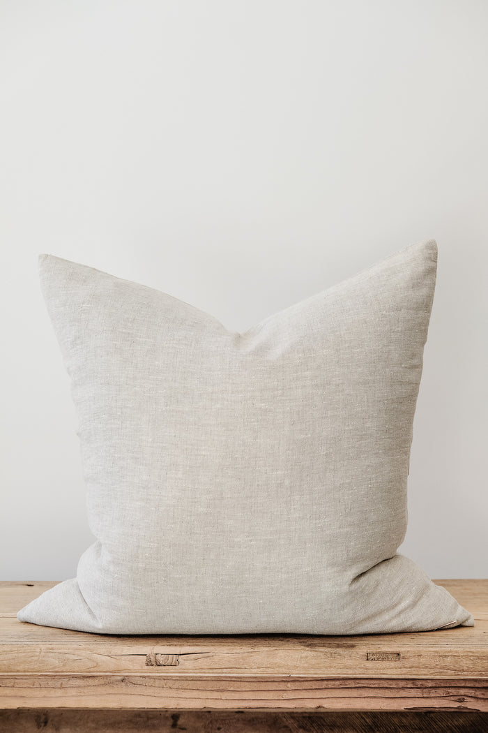 Front view of No. 50 - Natural Linen Pillow on an Antique Bench against a white wall. - Saffron and Poe