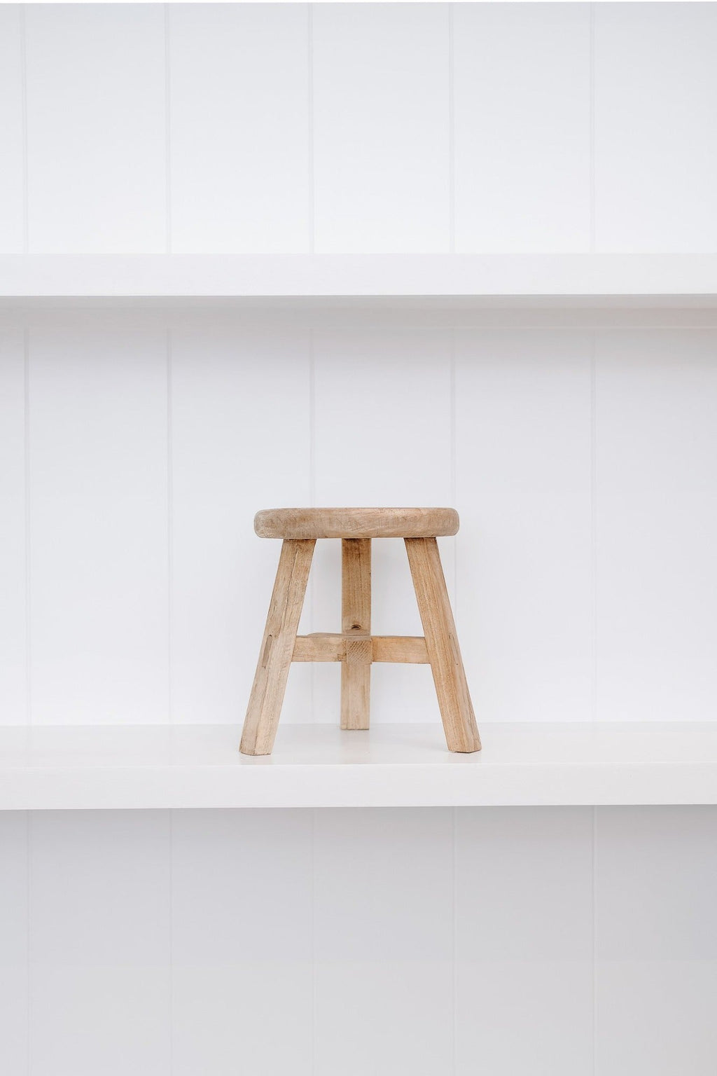 Petite vintage round wooden stool made from reclaimed elmwood with traditional Chinese design on white shelf