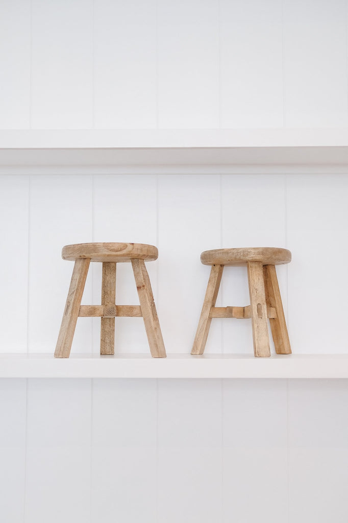 Two petite round stools against white background on white shelves. - Saffron and Poe