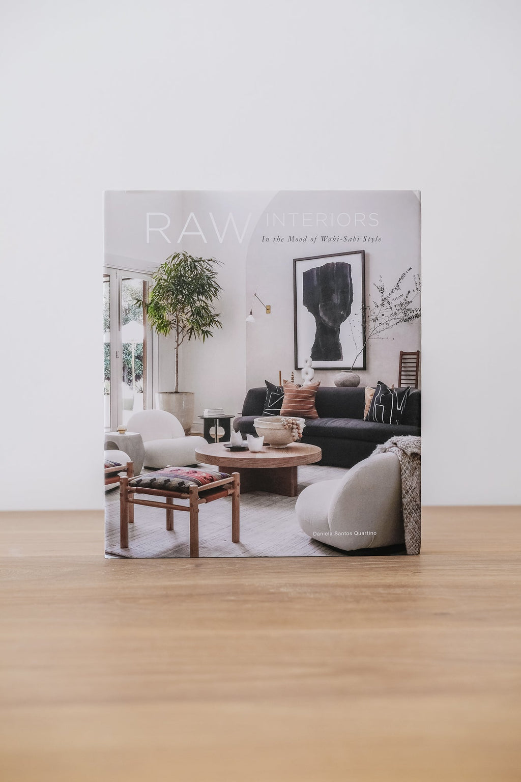 Book cover of Raw Interiors featuring a minimalist Wabi-Sabi styled living room with modern furniture and natural decor.