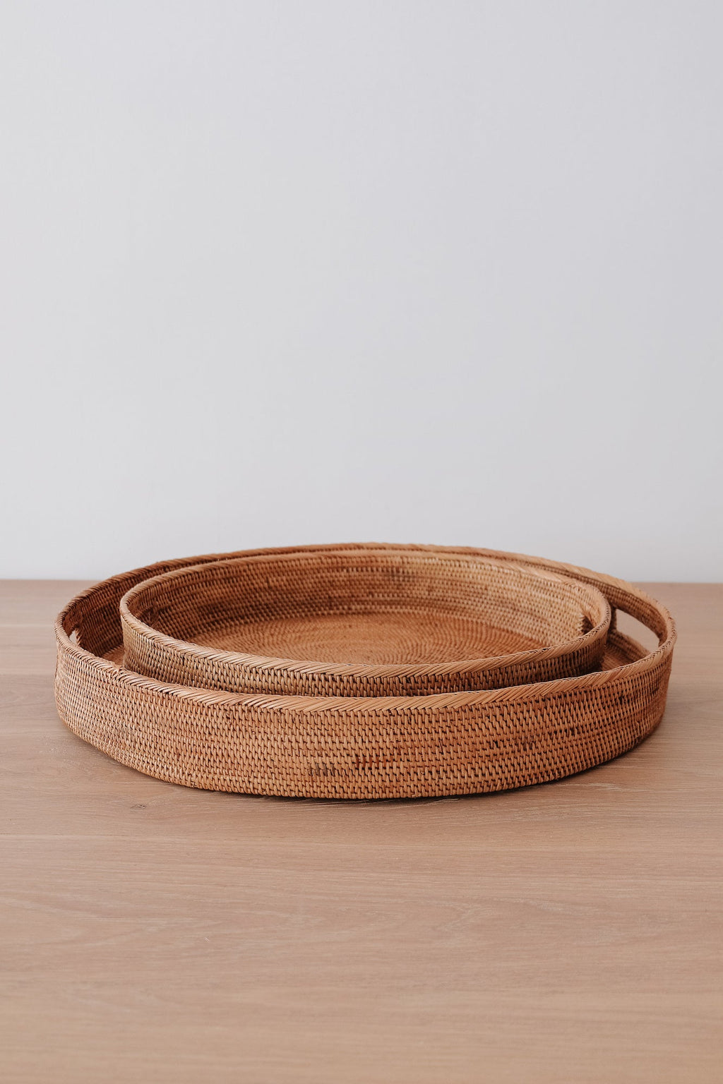 Round Tenganan Basket Trays set of 2 handwoven from natural Ata reed with intricate weaving and warm golden hue stacked on wooden surface