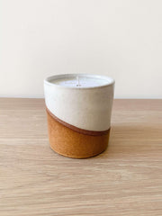 Uzumati Ceramic Desert candle in two-tone stoneware vessel with white glaze top and rust base on wooden surface