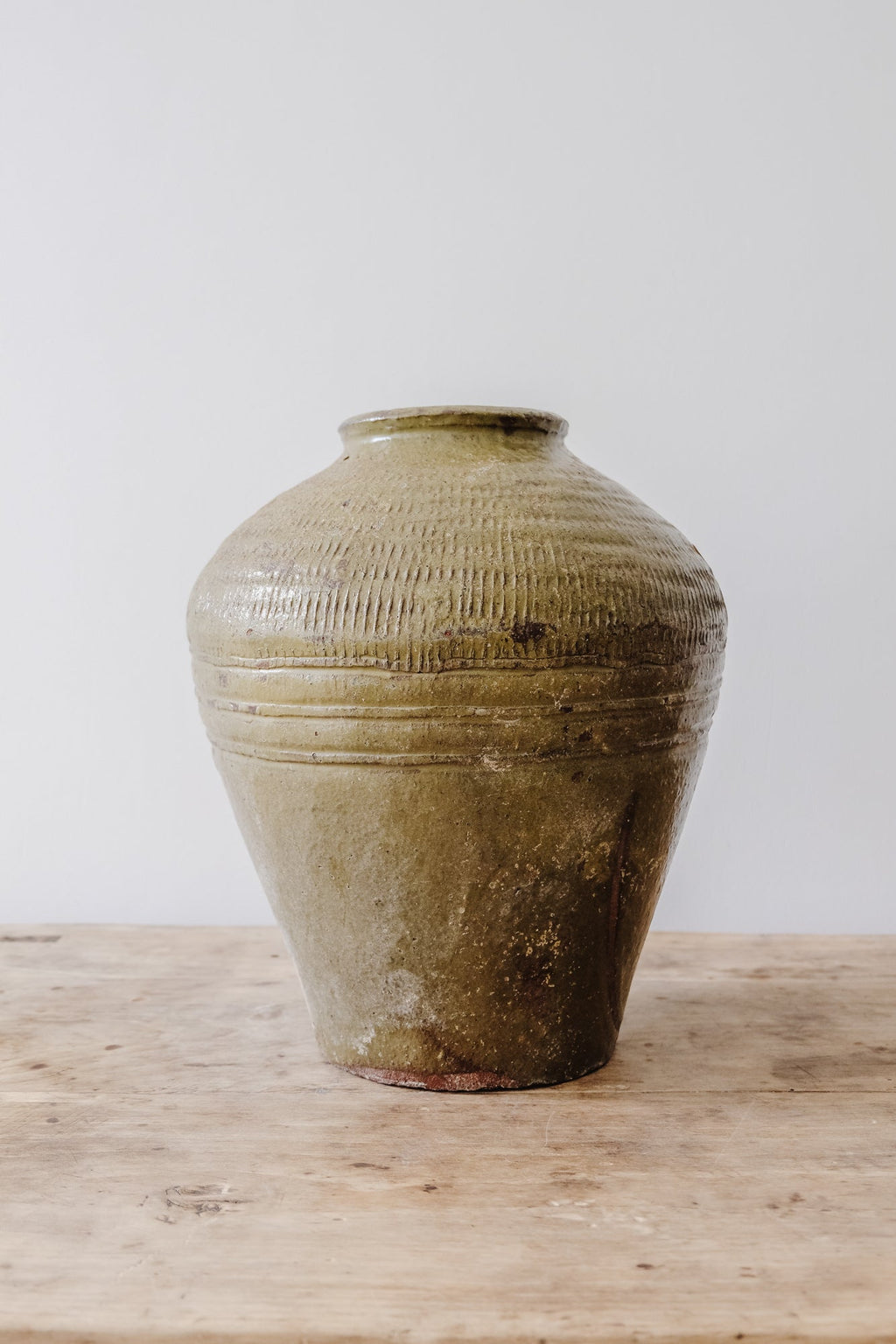 Antique handmade vintage Mijiu jar clay vessel on wooden surface