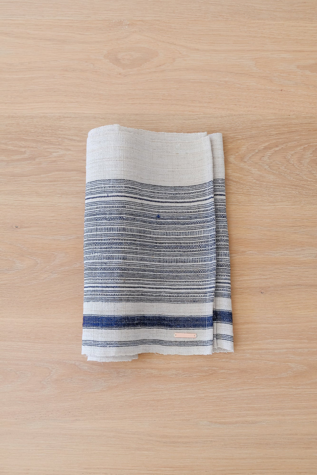 Vintage striped table runner with indigo and cream hemp fabric folded on wooden surface