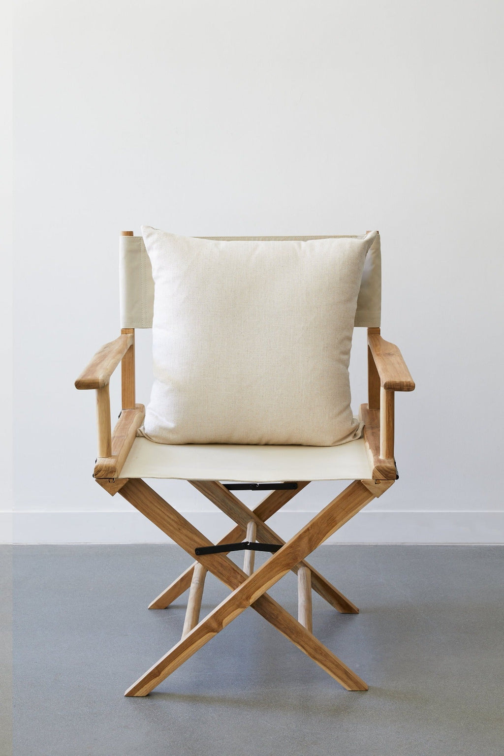 Cream linen chevron pillow on wooden director's chair in minimalist room