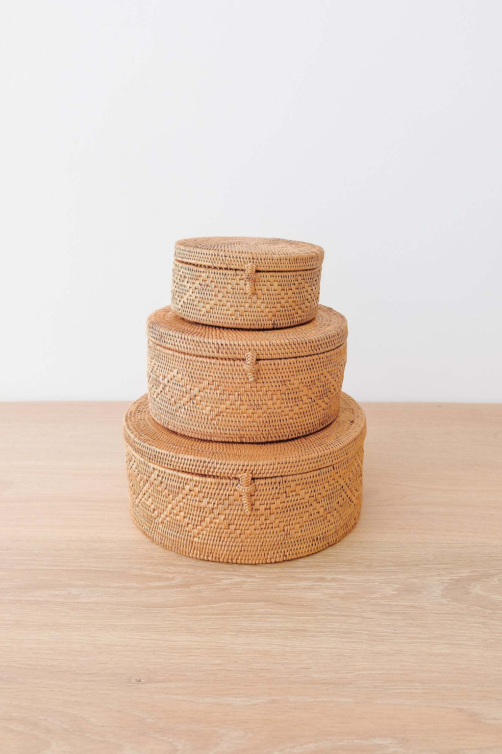Stacking Tenganan baskets handwoven in diamond pattern made from natural Ata reed displayed on wooden surface