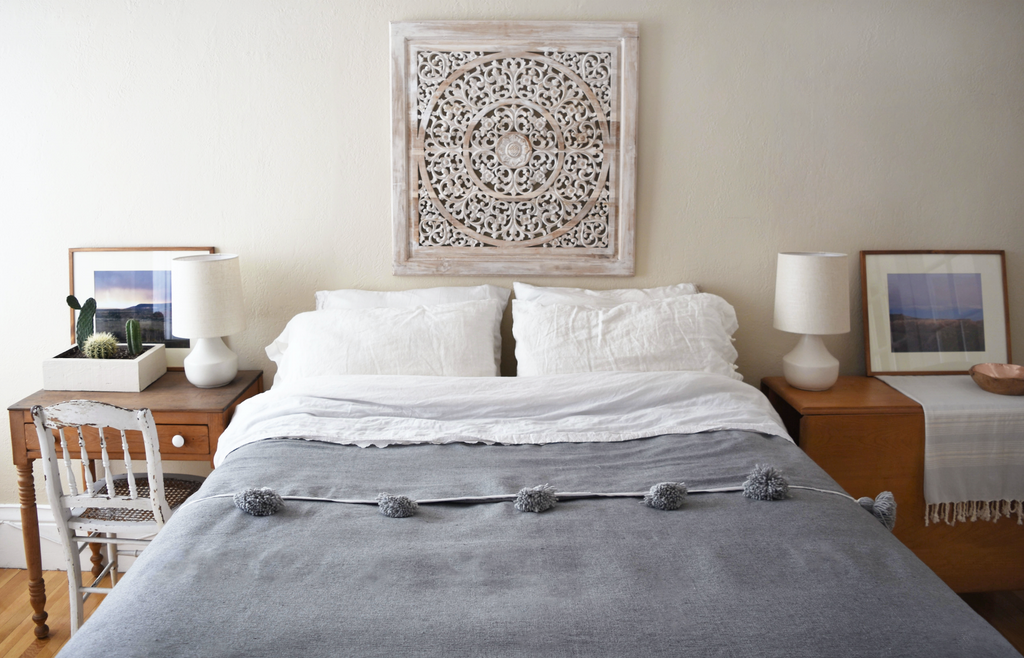 Grey Moroccan Pom Bed Throw with oversized pom tassels on a white bed in a bohemian style bedroom