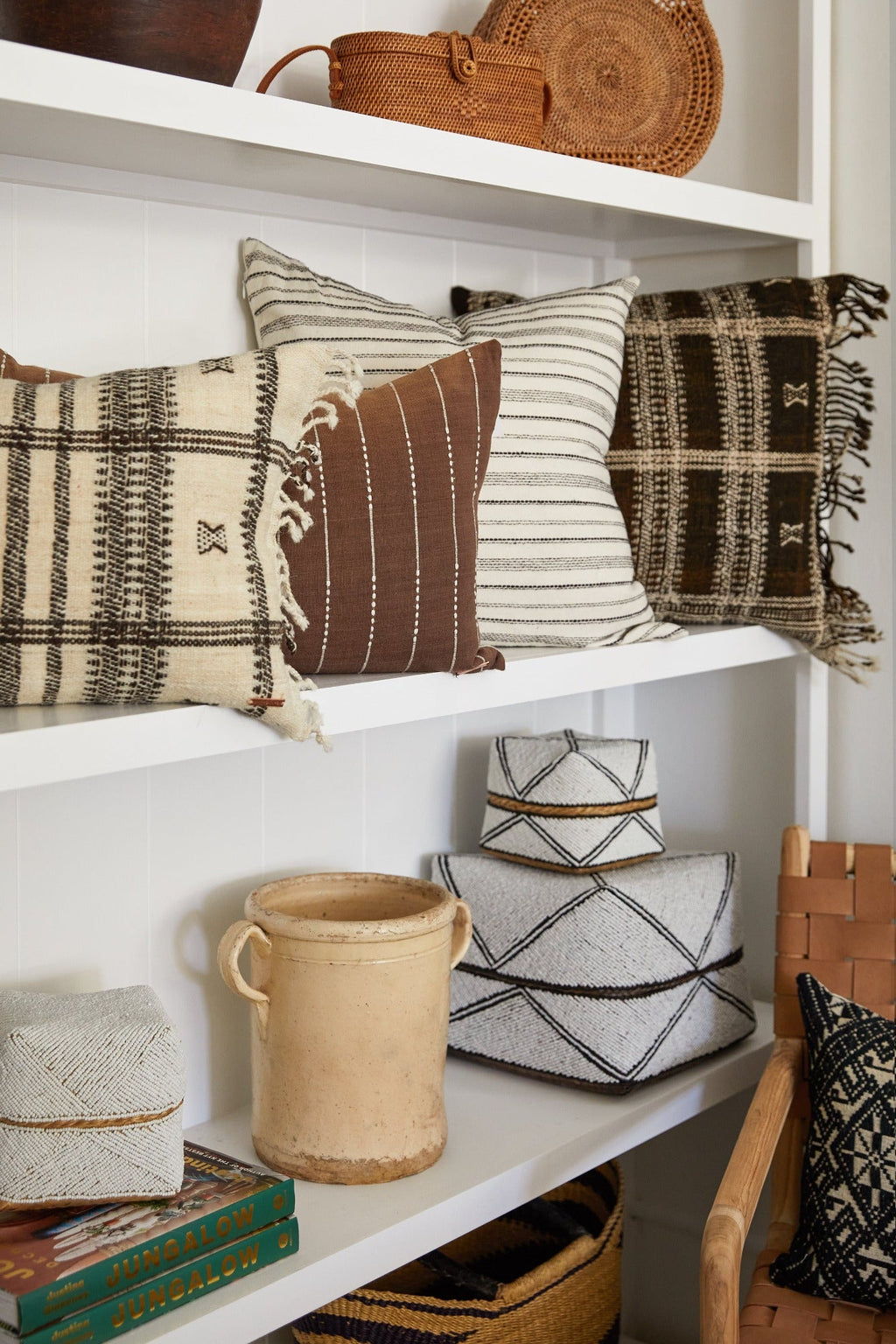 Rustic Italian confit pot displayed on white shelf with patterned pillows and woven baskets