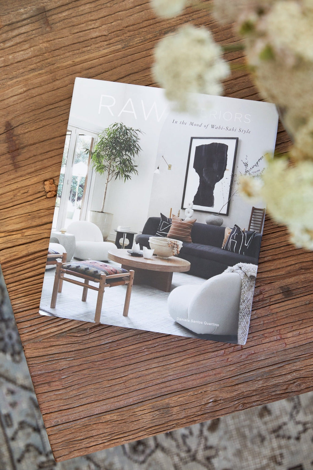Book titled Raw Interiors featuring minimalist Wabi-Sabi style living room on wooden table