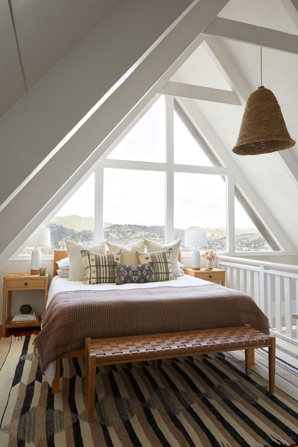 Handwoven Bhujodi bed throw in rust draped on bed in bright attic bedroom with rustic decor