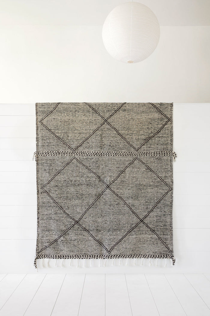 Moroccan flat weave Kilim rug with geometric diamond pattern and fringe, 6'-10" x 10'-3" displayed on white wall under paper lantern