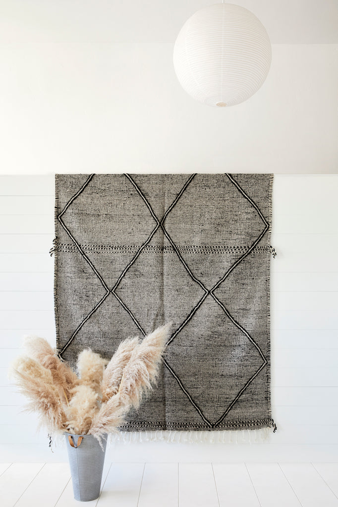 Styled photo of No. 24 - Moroccan Flat Weave Kilim Rug against a white wall with pampas grass. - Saffron and Poe