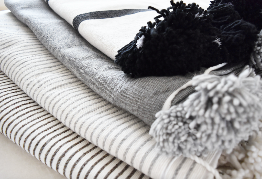 Folded Moroccan Pom Bed Throws in light grey and white stripes with oversized pom tassels