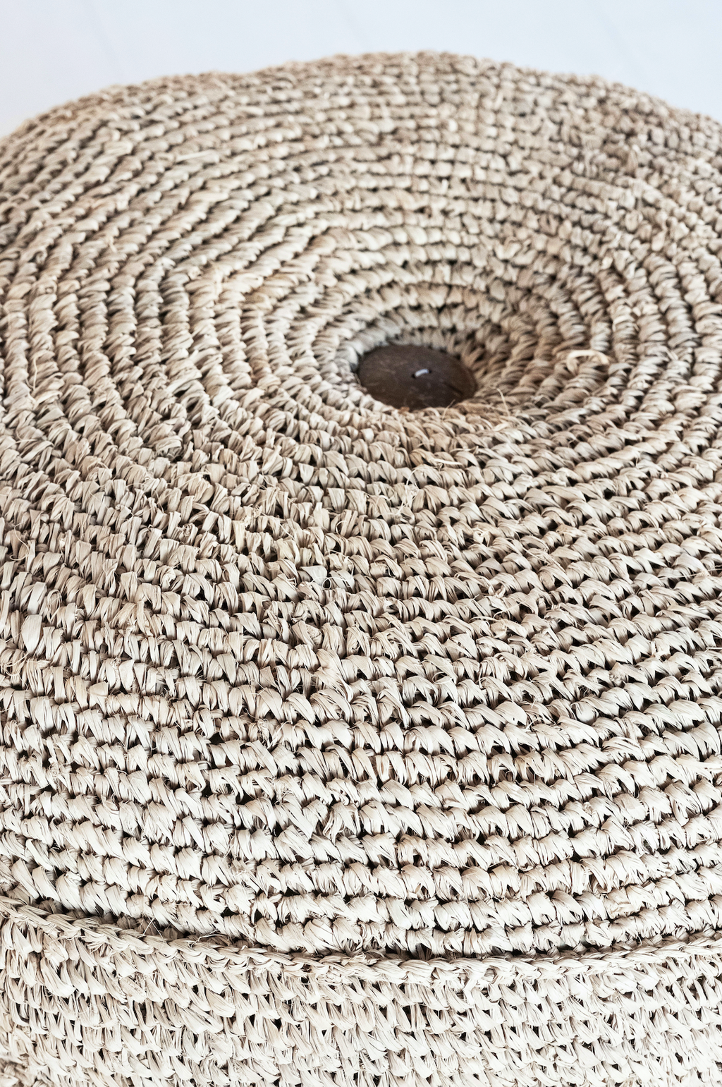 Close-up of a natural woven hyacinth pouf made from dried water hyacinth fibers with a textured circular pattern.
