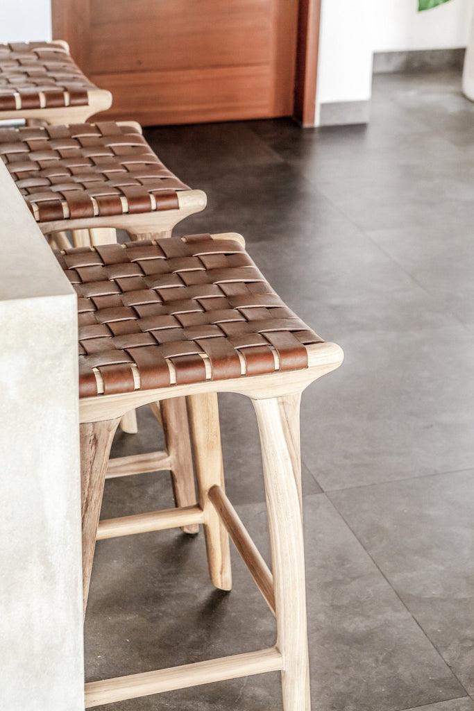 Three counter height Backless Woven Leather Counter dining stool at the kitchen counter. Handmade in Bali using Teak wood and vegetable-tanned leather imported from Java. - Saffron and Poe