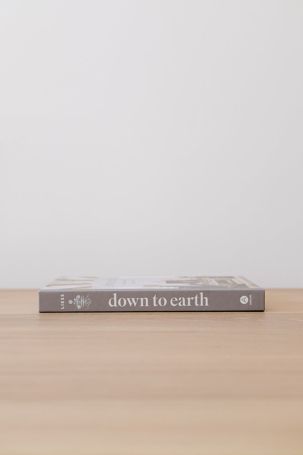 Down to Earth book by Lauren Liess on wooden surface against white background