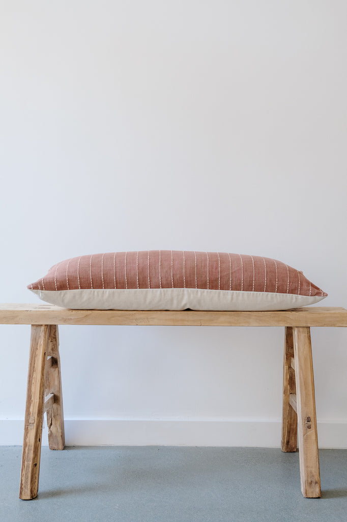Side view of No. 13 - Hmong Hemp Lumbar Pillow - Extra Long on an Antique Bench against a white wall. - Saffron and Poe