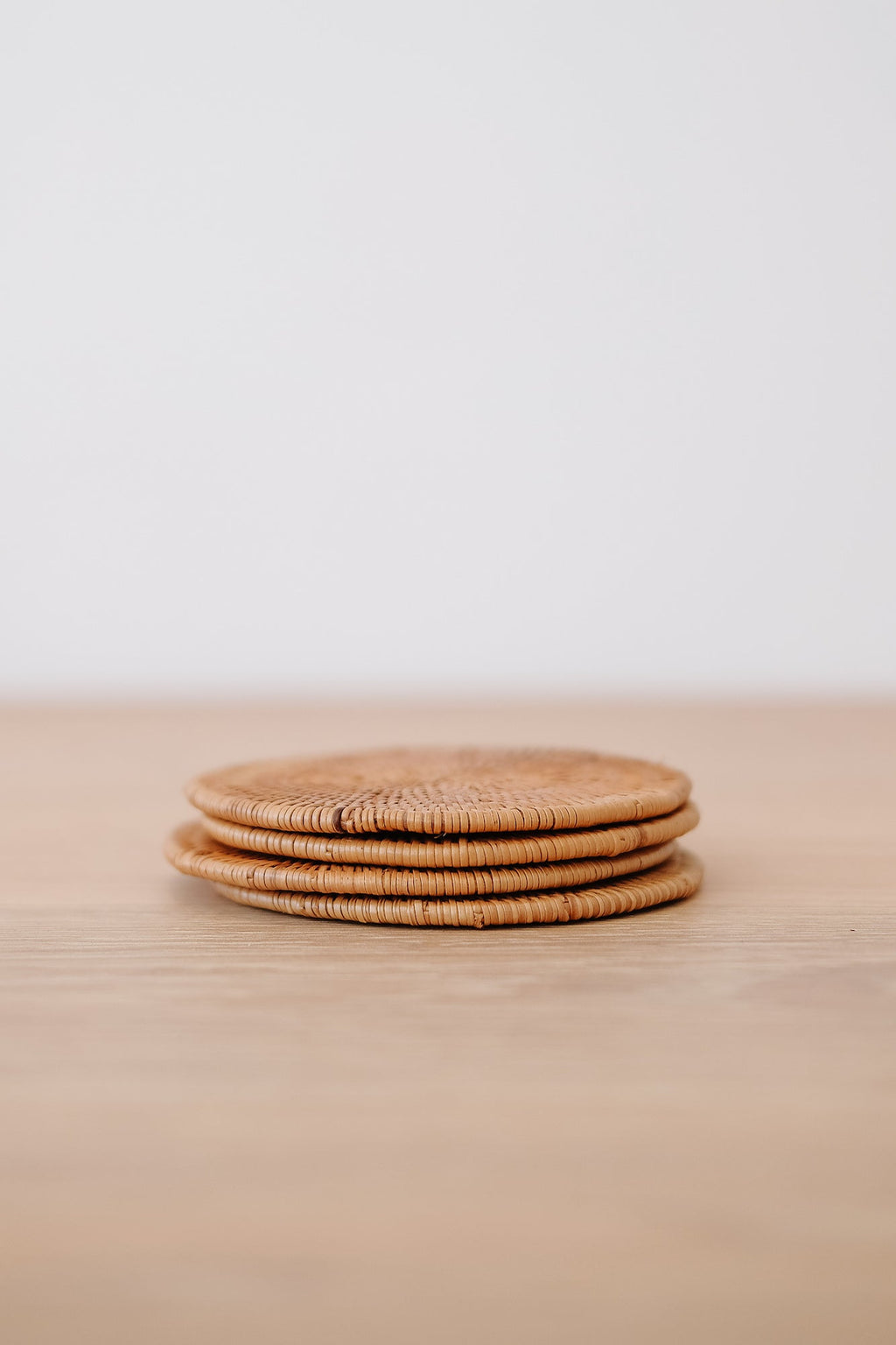 Set of 4 handwoven Tenganan Coasters made from natural Ata reed, stacked on wooden surface