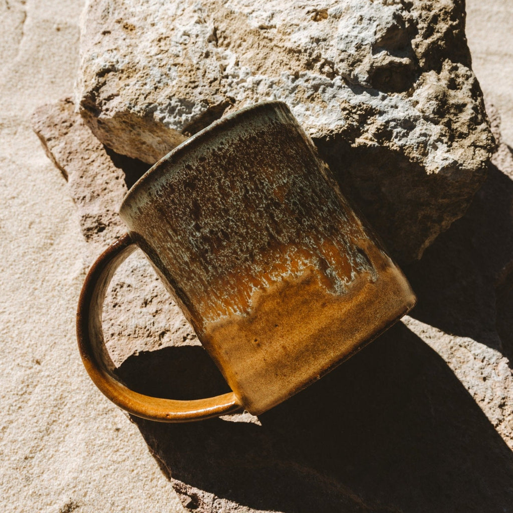 Handcrafted Uzumati Tortoise Mug with earthy glaze inspired by Joshua Tree desert tortoise placed on rugged stone