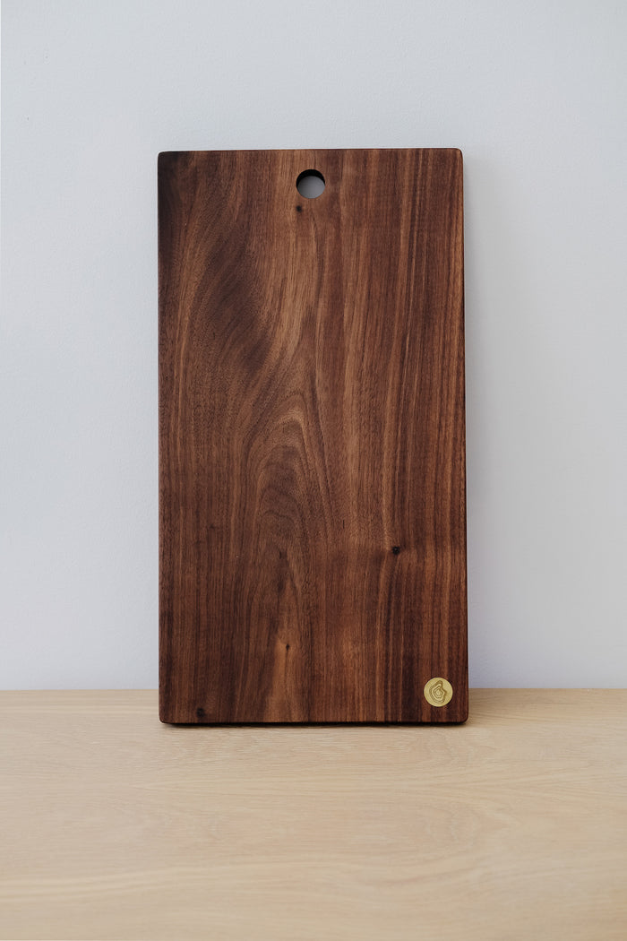 Front view of Studio Inko Walnut Cutting and Serving Board against a white wall. - Saffron and Poe