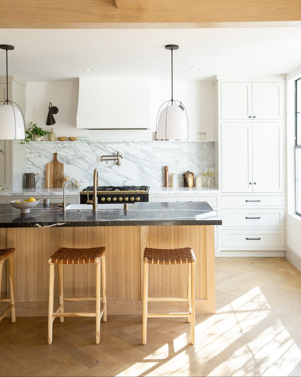Backless woven leather counter stools with saddle leather straps and teak wood frame in a modern kitchen setting