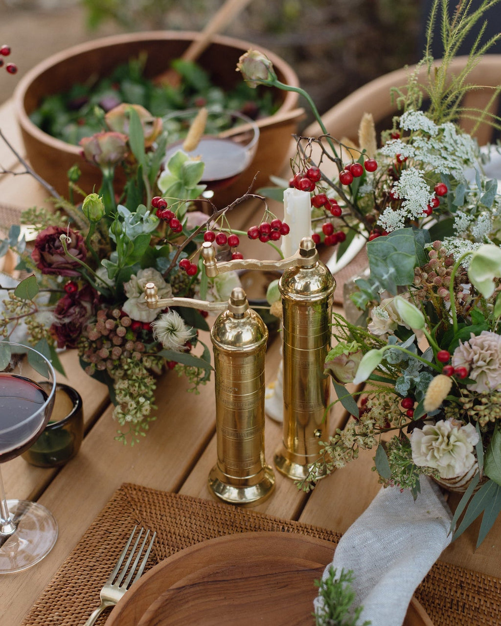 Atlas Brass Salt and Pepper Grinder Set on wooden table with flowers and wine glass
