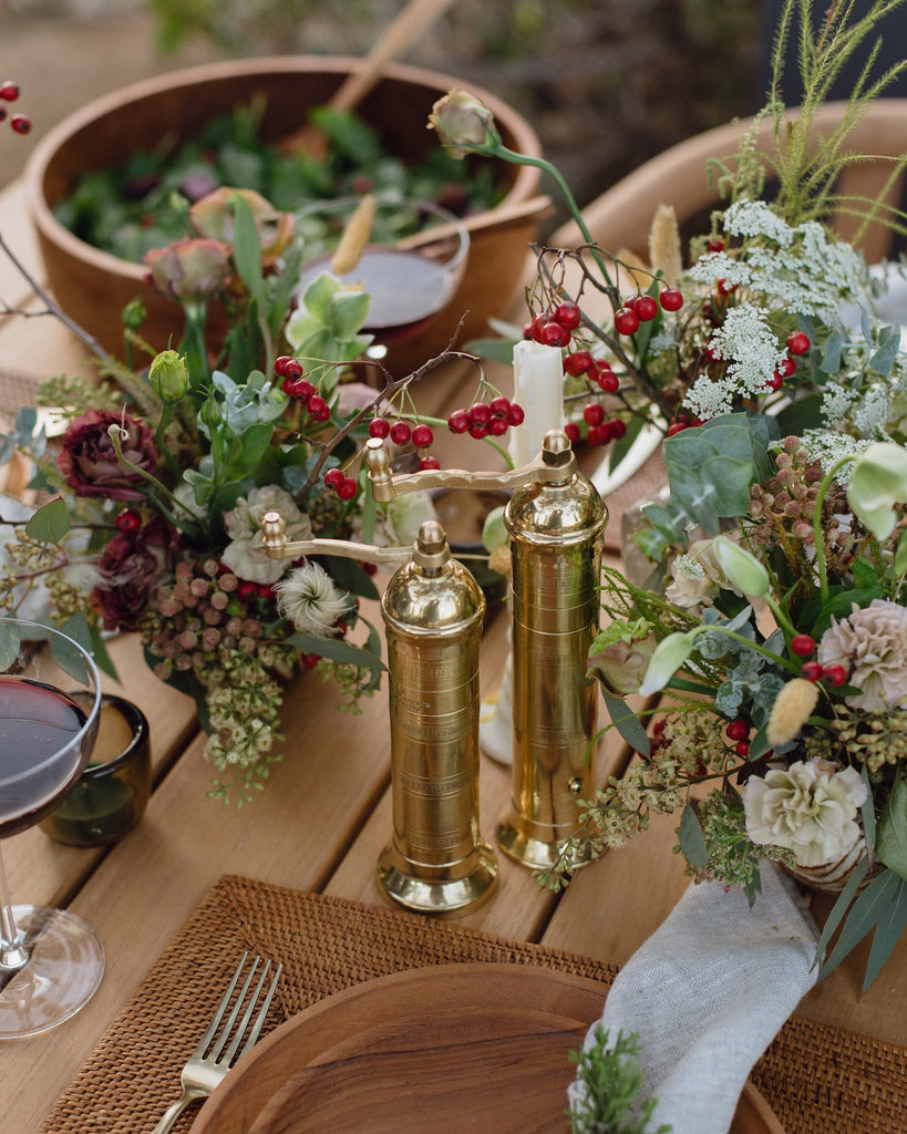 Atlas Brass Salt and Pepper Grinders on an outdoor table with Teak Plates and florals