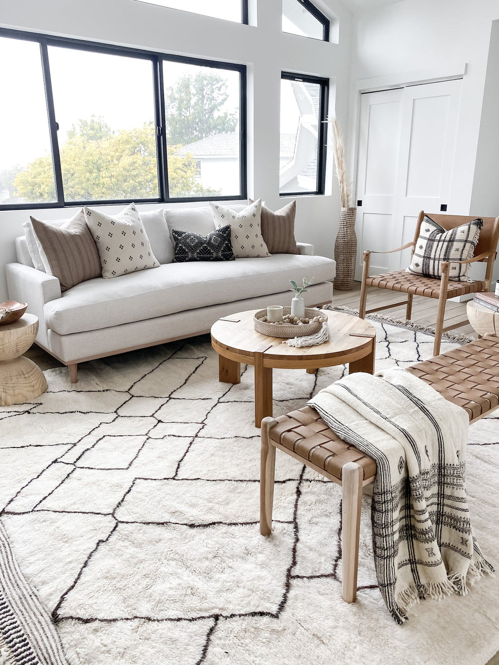 Beige embroidered pillow on sofa in modern living room with neutral decor and textured rug