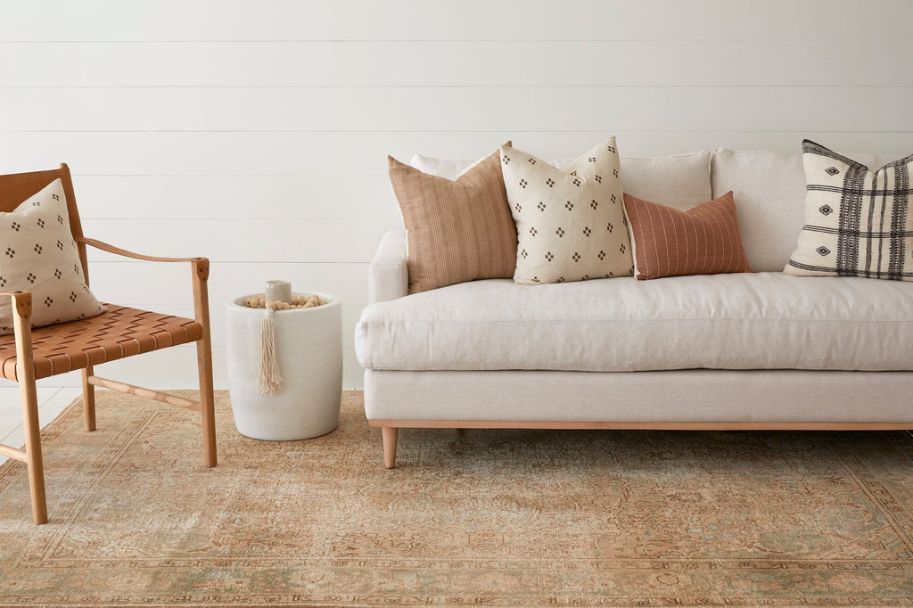 Beige embroidered pillow with subtle patterns on a neutral sofa in a cozy living room setting