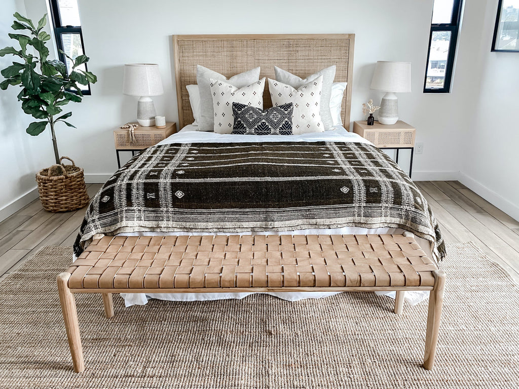 Dark brown handwoven Bhujodi blanket with white pastoral motifs on a bed in a modern bedroom setting