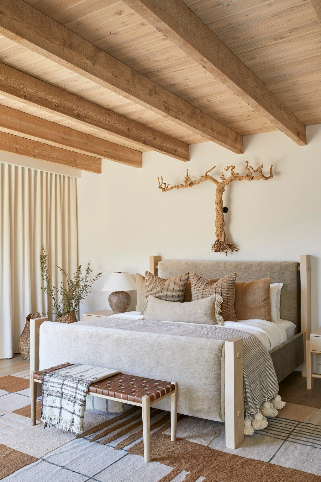 Handwoven Bhujodi Blanket draped over bench in neutral modern bedroom with wooden beams and natural decor