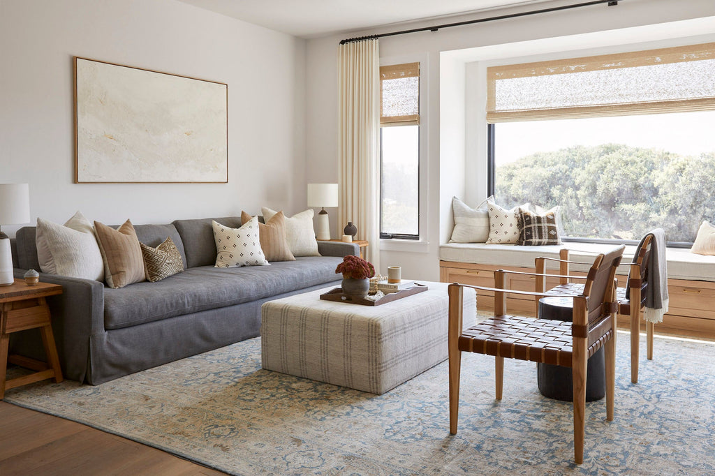 Living room with gray sofa, wooden chairs, and brown checkered pillow accents