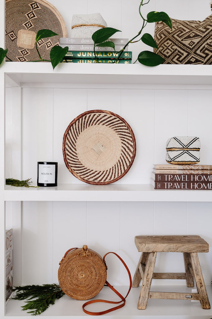 Styled view of La Botica Nolita Candle on a decorated shelf with hand woven baskets. - Saffron and Poe