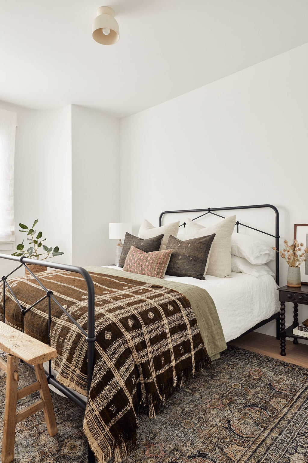 Cozy bedroom featuring natural linen pillows on bed with patterned blanket and rustic decor