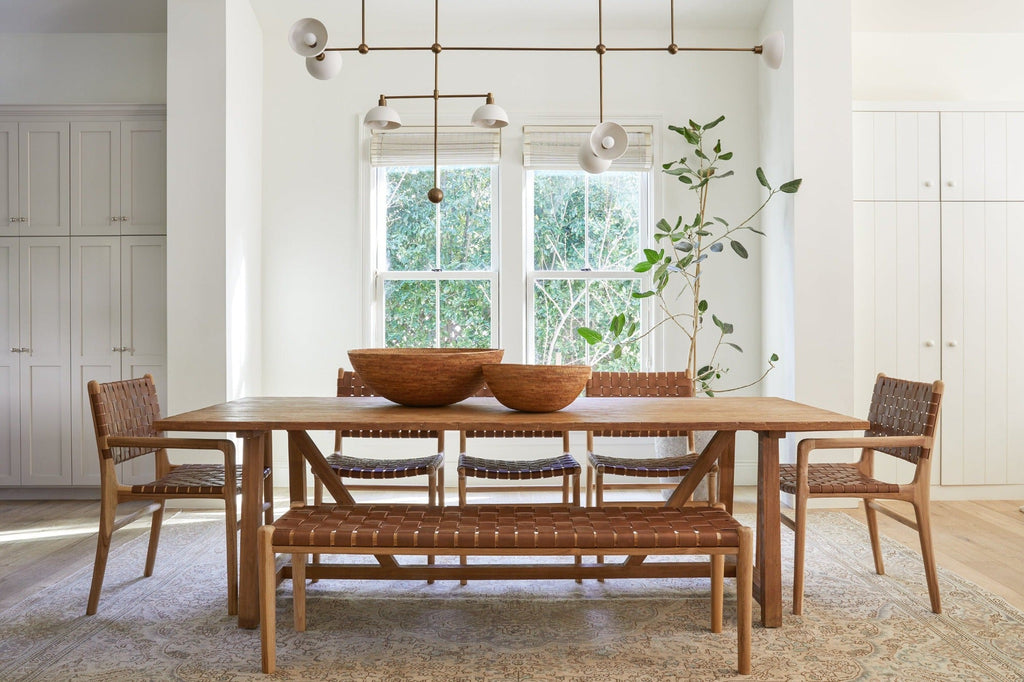 Woven leather bench with teak frame and saddle-colored leather straps in a bright dining room setting